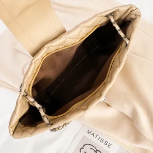Detail view of the quilted beige chain bag interior with a brown lining and zipper pocket
