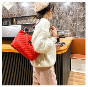 Detail of red quilted leather shoulder bag with chain strap and metal turn-lock closure