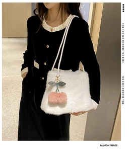 Dettaglio borsa shopper in peluche bianca con ciondolo a ciliegia su abito nero