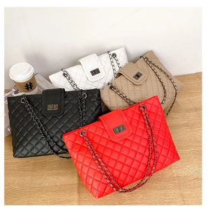 Detailed display of four quilted chain bags in black, white, khaki, and red on a desk