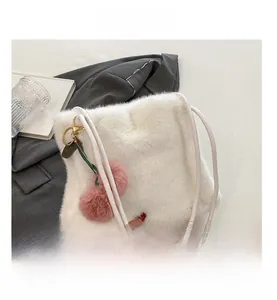 Dettaglio borsa in ecopelliccia bianca con ciondolo a pompon rosa e nastro di seta elegante