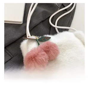 Dettaglio della borsa a spalla in peluche bianca con ciondolo a ciliegia e foglie in pelle