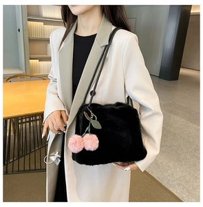 Dettaglio borsa tote in ecopelliccia nera con ciondolo a ciliegia rosa e tracolla in pelle