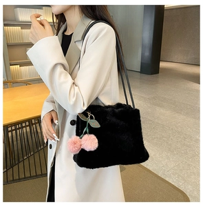 Dettaglio della borsa tote in ecopelliccia nera con un ciondolo a ciliegia in peluche rosa