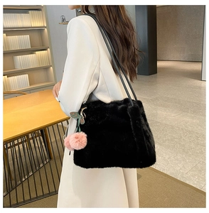 Dettaglio della borsa tote in peluche nera con ciondolo a ciliegia rosa su donna