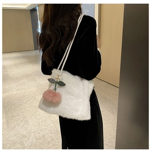 Dettaglio della borsa tote in peluche bianca con ciondolo a ciliegia indossata da una modella