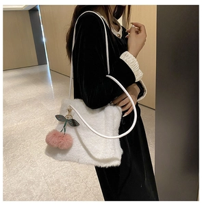 Dettaglio della borsa tote bianca in peluche con ciondolo a ciliegia e tracolla in pelle