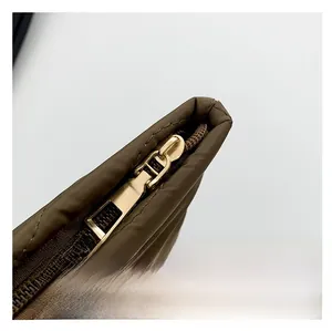 Detail van de gouden rits en donkerbruine gewatteerde nylon stof van de tas