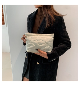 Close-up of white quilted handbag with large flower pattern and secure metal zipper