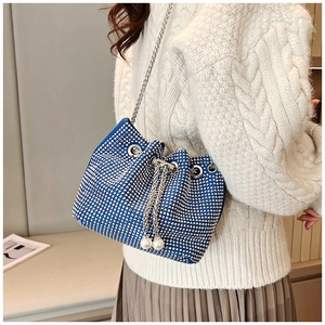 Détail macro du sac seau bleu en strass avec chaîne argentée et cordon en perles