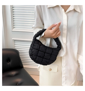 Detail of black quilted cloud bag showing the textured puffy fabric and handle on a model
