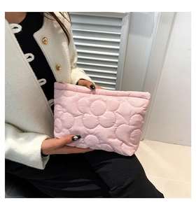 Detail of pink quilted handbag with 3D floral pattern and secure metal zipper closure