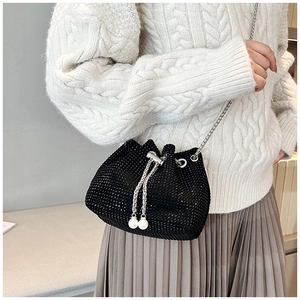 Détail d'un sac seau noir orné de strass avec cordon en perles et bandoulière en chaîne