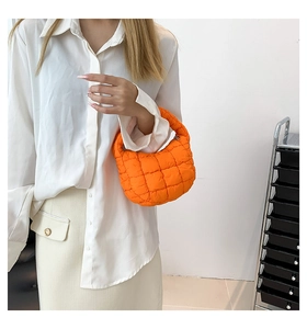 Detail of bright orange quilted cloud bag showing the puffy plaid texture and handle