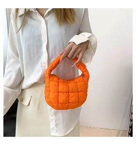 Detail showing the vibrant orange quilted nylon handbag with a puffer texture and soft handle