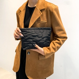 Chic black quilted handbag with wave texture held by a model in a brown blazer