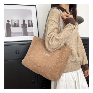 Détail du sac fourre-tout en peluche camel avec étiquette mode porté par un mannequin