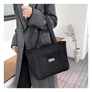 Dettaglio della borsa tote nera in pile con il logo FASHION sulla tasca anteriore