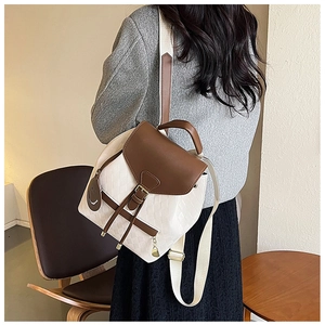 Détail d'un sac à dos blanc matelassé avec cuir marron et pendentif smiley
