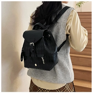 Détail d'un sac à dos noir matelassé avec boucle dorée et fermeture à cordon