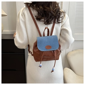Detail of mini patchwork backpack with brown leather, blue denim cover and drawstring
