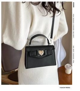 Détail du sac en cuir grainé noir avec fermoir cœur doré et design de nœud élégant
