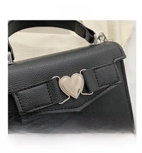 Détail du cuir grainé noir et de la boucle en métal argenté en forme de coeur