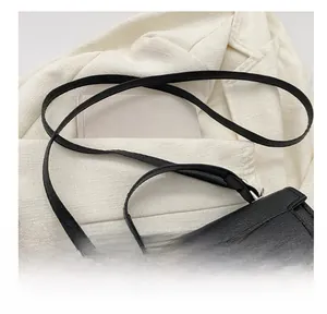 Détail du sac à main en cuir grainé noir avec boucle cœur argentée et bandoulière