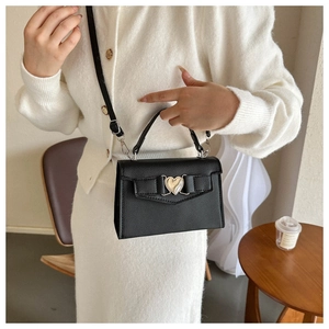 Détail du sac en cuir noir à motif litchi avec fermoir cœur doré et bandoulière fine