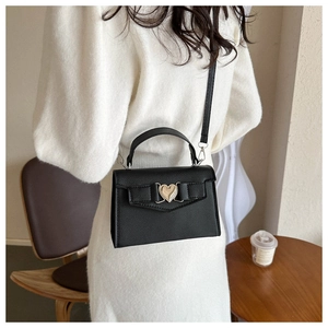 Détail du sac à main en cuir grainé noir avec fermoir métallique en forme de cœur doré