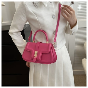 Close-up of bright pink leather shoulder bag with gold metal ring lock on a white jacket