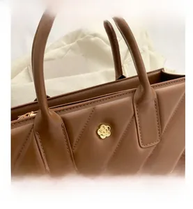 Close-up of brown quilted leather bag with elegant gold flower metal ornament