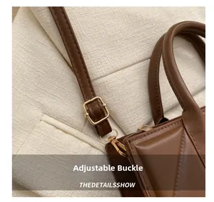Detail of adjustable golden buckle and lobster clasp on dark brown leather handbag strap