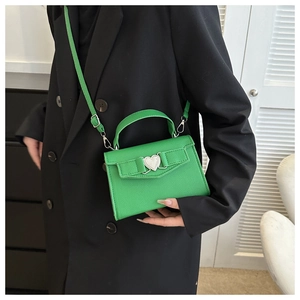 Détail du sac en cuir grainé vert avec une boucle argentée en forme de cœur