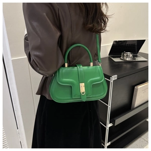 Detail of a bright green shoulder bag with a gold twist-lock closure on a leather outfit