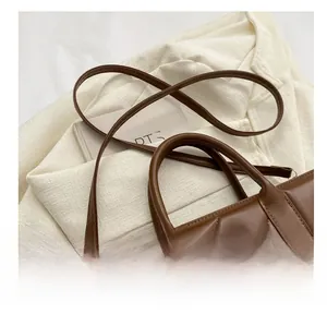 Close-up of quilted brown leather handbag with golden flower buckle and adjustable strap