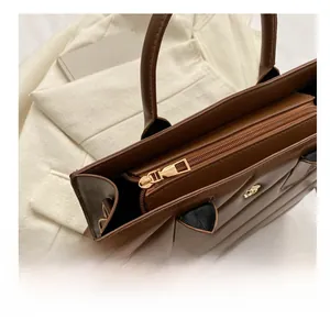 Close-up of brown leather handbag with smooth gold metal zipper and lion head logo