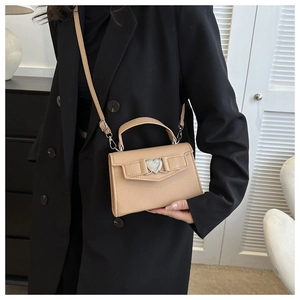 Détail du mini sac en cuir kaki avec un élégant fermoir en métal argenté en forme de cœur