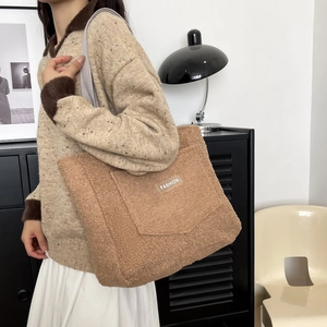 Sac fourre-tout marron en peluche avec étiquette de mode porté par un mannequin chic