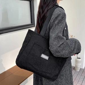 Grand sac cabas en peluche noire avec étiquette FASHION porté à l'épaule avec style