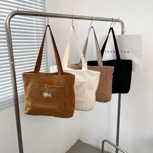 Grande borsa tote minimalista in pile in quattro colori appesa su un appendino