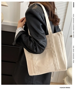 Détail du sac fourre-tout en toile blanc cassé avec sangles renforcées sur veste en cuir