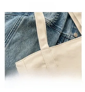 Vue détaillée des coutures renforcées sur un sac fourre-tout en toile blanc cassé tissée