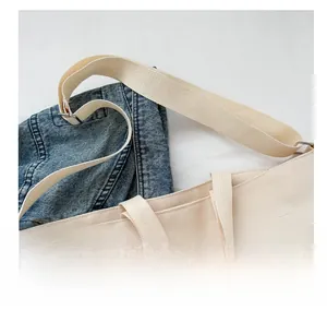 Detail view of adjustable wide shoulder strap and metal buckle on canvas tote bag