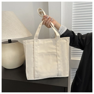 Gros plan sur un cabas en toile blanc crème avec poche avant et texture de tissu robuste