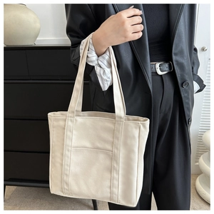 Détail du sac cabas en toile blanc cassé avec sangles renforcées et poche frontale