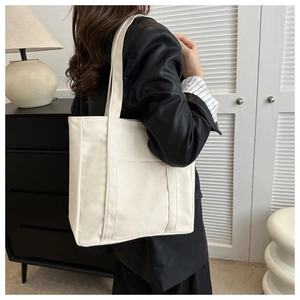 Sac fourre-tout en toile crème minimaliste avec poche latérale dans un intérieur moderne