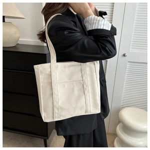 Photo de mode d'un sac cabas en toile blanche avec poche externe sur l'épaule