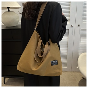 Detail of khaki canvas tote bag with fashion label and reinforced shoulder strap stitching