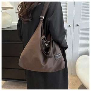 Detail of dark brown canvas tote bag featuring fashion label and adjustable strap